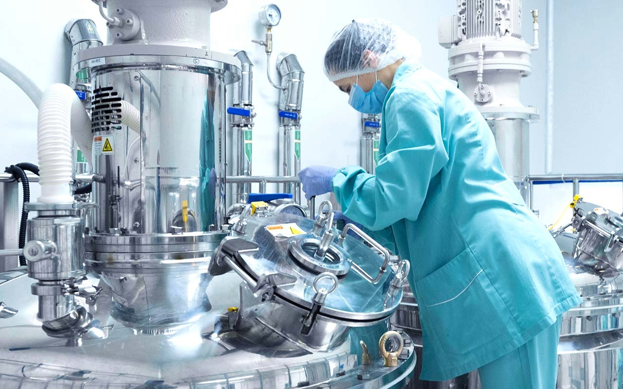 Technician operating stainless steel process equipment in a pharmaceutical or chemical plant, illustrating cleanroom-compatible sealing for FFKM o rings.